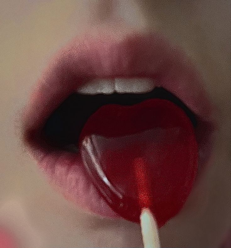 a woman's lips with a candy lollipop in her mouth and the lip is red