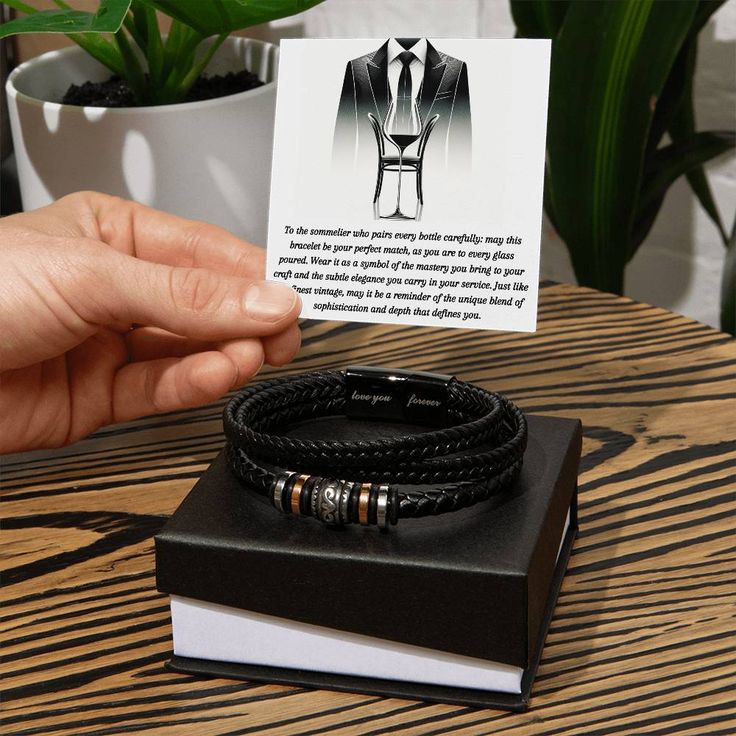 Introducing the Sommelier's Signature Bracelet — a symbol of refined taste and professional elegance. Crafted with the finesse of a master vintner's touch, this bracelet is designed to parallel the subtlety and depth of a fine wine. Its woven leather exudes a vintage charm, while the stainless steel accents mirror the polished look of a sommelier at work. Encased in a handsome display box, complete with a personalized message card, it makes the perfect accessory for the discerning sommelier who Timeless Stainless Steel Bracelets For Formal Occasions, Timeless Stainless Steel Bracelet For Formal Occasions, Timeless Stainless Steel Formal Bracelet, Luxury Stainless Steel Bracelet For Formal Occasions, Elegant Silver Leather Bracelet With Jubilee Style, Elegant Silver Leather Jubilee Bracelet, Classic Black Leather Bracelet For Gift, Classic Black Leather Bracelet Gift, Elegant Stainless Steel Wristband Bracelet