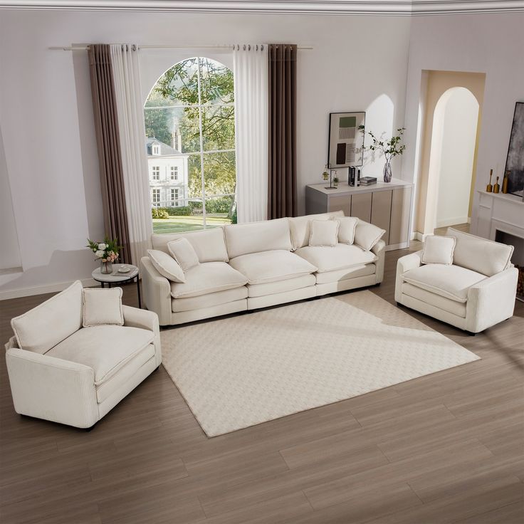 a living room with white furniture and wood floors