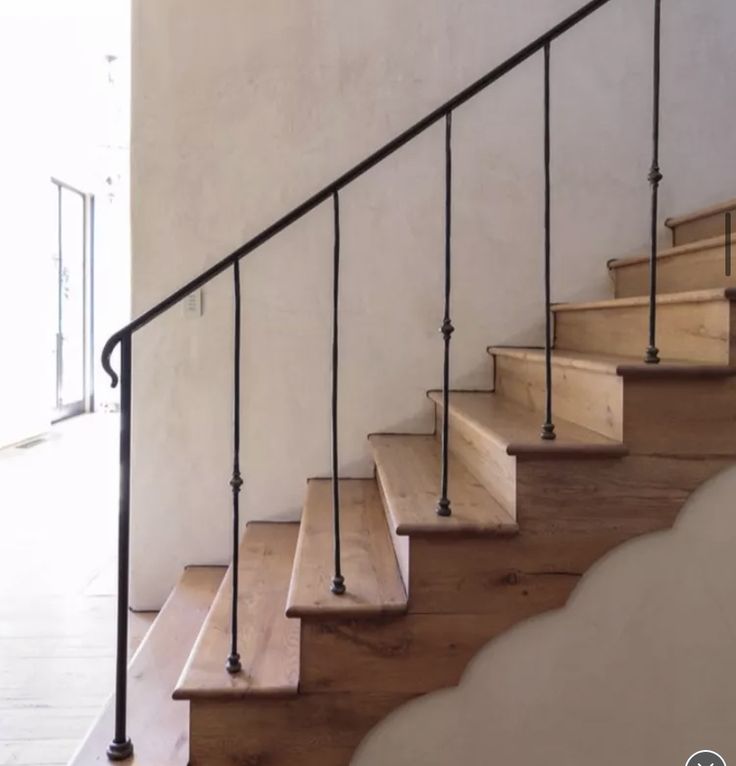 a set of stairs leading up to an open door in a house with white walls and wood floors