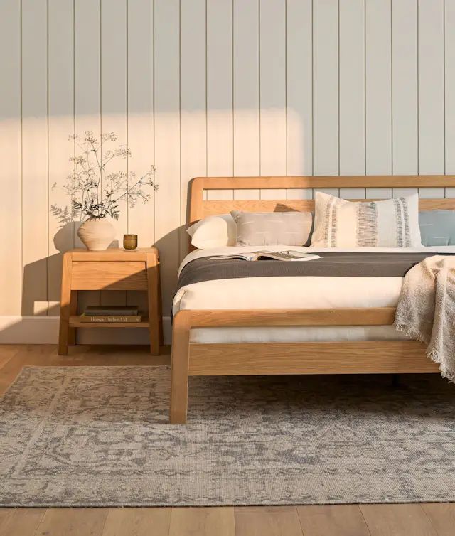 a wooden bed sitting on top of a hard wood floor next to a night stand