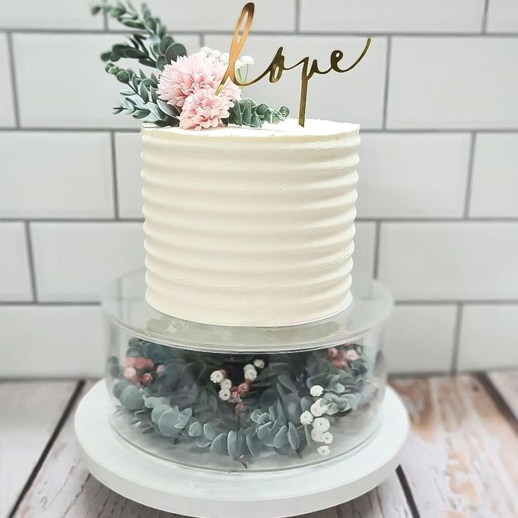 a white cake with flowers and greenery on top