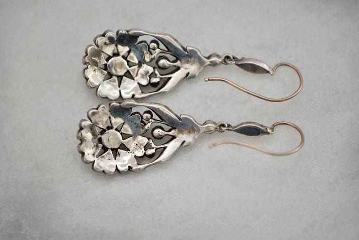 "Striking pair of English Victorian sterling and paste flower dangle earrings, circa 1840s - 1860s. The design is exquisite, comprised of a lovely daisy design of eight heart shaped petals with a larger round paste stone in the middle. There are also eleven more paste stones on the top of the earring. Materials - Sterling silver, paste stones and gold wire. Weight is 9.59 grams. Hallmarks - None. Condition - Very good antique condition. All stones are sparkling and clear. Measurements - Earrings Vintage Ceremonial Drop Earrings, Victorian Style Ceremonial Dangle Earrings, Vintage Drop Earrings For Ceremonial Occasion, Antique Drop Earrings With Historical Design, Vintage Ceremonial Earrings With Intricate Design, Ceremonial Vintage Earrings With Intricate Design, Antique Earrings With Historical Design, Vintage Earrings With Historical Design, Victorian Engraved Earrings For Formal Occasions