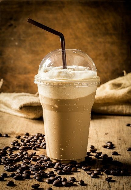 there is a drink with a straw in it and coffee beans on the table next to it