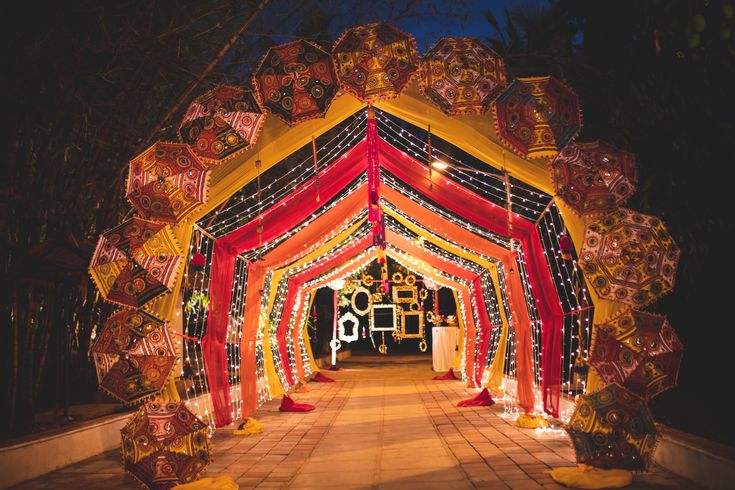 a decorated archway with lights and decorations on the sides is lit up for an outdoor event