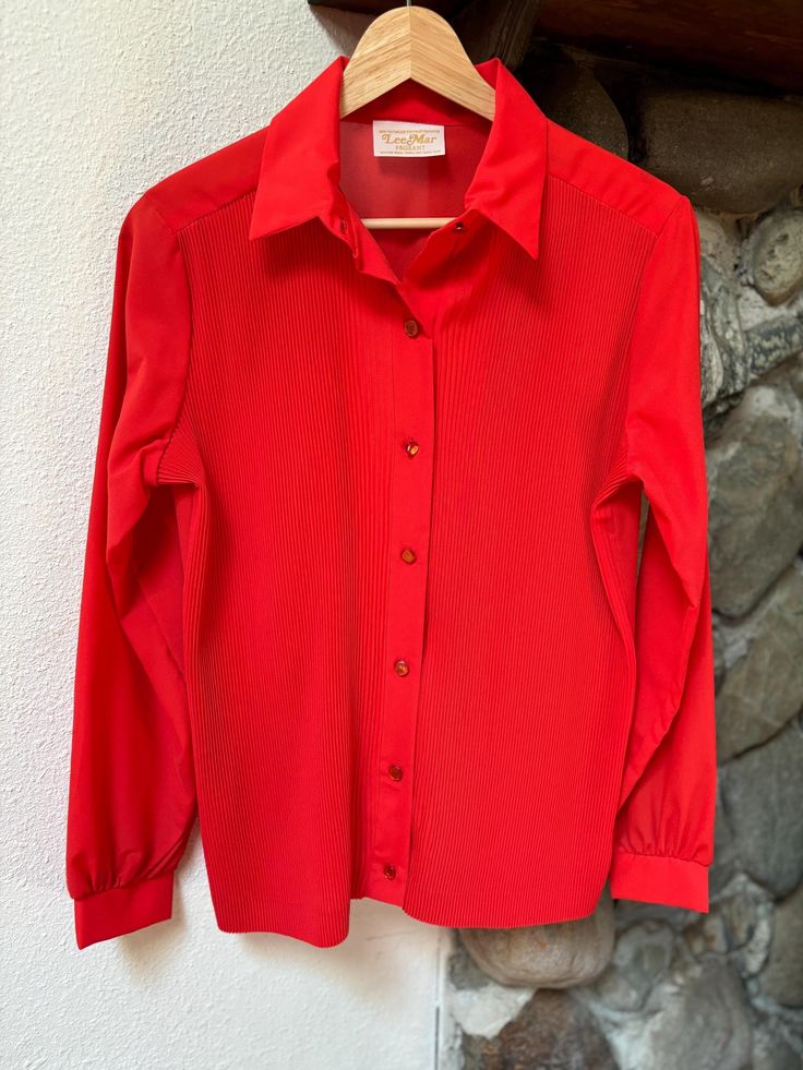 Pristine condition and such a vibrant red color! Brand: Lee Mar Pageant Size: No size tag, fits like XS or S (see measurements below) Material: 100% texturized fortrel polyester  Color: Red Condition: Excellent Origin: Not listed on tag Flat Lay Measurements: Length (shoulder to bottom hem) - 25 inches Chest (pit to pit across) - 20 inches Sleeve Length - 22.5 inches Tags: vintage classy bright red bold blouse button up work business elegant date night sheer 70s *Shop Note: Items are secondhand/preworn and may have signs of natural wear. Any noticeable flaws will be called out in the description/photos. Message me with any questions! Red Long Sleeve Office Top, Red Long Sleeve Top For Office, Classic Red Blouse For Fall, Red Office Shirt For Fall, Red Shirt For Office In Fall, Red Shirt For Office Wear In Fall, Vintage Red Long Sleeve Blouse, Red Button-up Blouse With Button Cuffs, Classic Red Tops With Button Cuffs