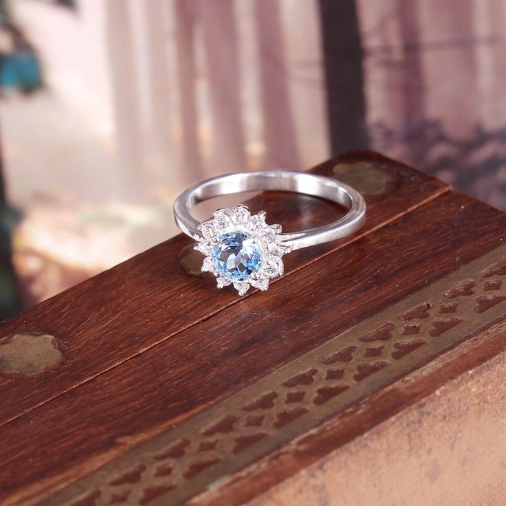 a ring sitting on top of a wooden box with a blue stone in the center