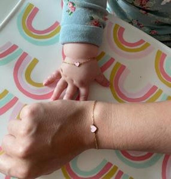 "A gold colored sterling silver bracelet with a colored enamel heart. This dainty chain bracelet matching set is perfect for mommy & baby! The standard size for the mommy bracelet is 5.75\" + 1\" Please select your baby wrist size in the option below along with enamel color If you would like a custom size for the mommy bracelet or for Rosegold/Silver bracelet colors (other than the standard gold) please contact us immediately after placing your order. For inquiries and bundle discounts email ret Dainty Yellow Gold Heart Bracelet For Mother's Day, Dainty Pink Gold Jewelry For Everyday, Cute Gold Jewelry Gift For Mom, Cute Gold Jewelry As Gift For Mom, Cute Gold Jewelry For Mom's Gift, Cute Gold Jewelry For Mom, Everyday Heart-shaped Name Bracelet For Mother's Day, Dainty Hypoallergenic Name Bracelet For Mother's Day, Dainty Heart Bracelet With Adjustable Chain For Mother's Day