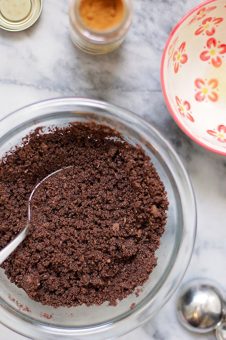 a glass bowl filled with dirt next to two spoons