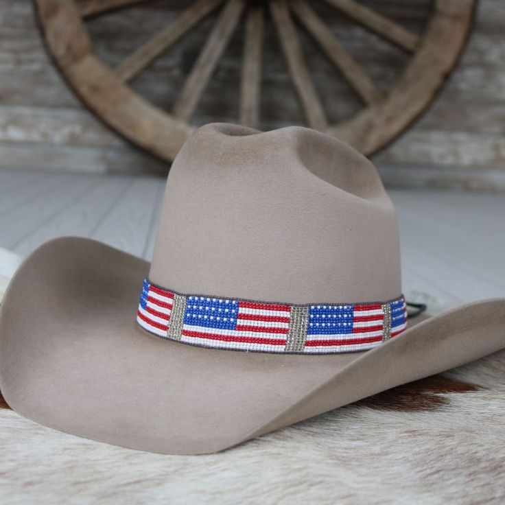 Celebrate your patriotism with this handcrafted beaded hat band showcasing a vibrant American flag design. Adjustable leather ties ensure a comfortable fit on any hat size. At 21 1/2" in length and 1 1/8" in width, this band adds a touch of American spirit to your look. Wear your love for the USA proudly wherever you go!    Adjustable with Leather ties  Length: 21 1/2 (not including ties)  Width: 1 1/8" American Style Adjustable Hat With Flat Brim, American Style Adjustable Flat Brim Hat, Adjustable Americana Hat For 4th Of July, Adjustable Americana Hat For Rodeo, Patriotic Adjustable Hat For Independence Day, Patriotic Adjustable Hats For Country Events, Adjustable Patriotic Hats For Country Events, Adjustable Patriotic Hat For Rodeo, Adjustable Americana Hats For Country Events