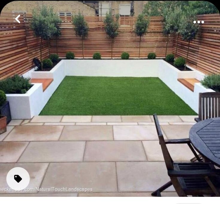 an outdoor patio area with grass and wooden fenced in planters on either side