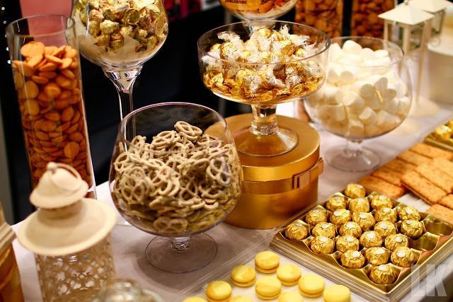 a table topped with lots of different types of desserts and candies next to wine glasses