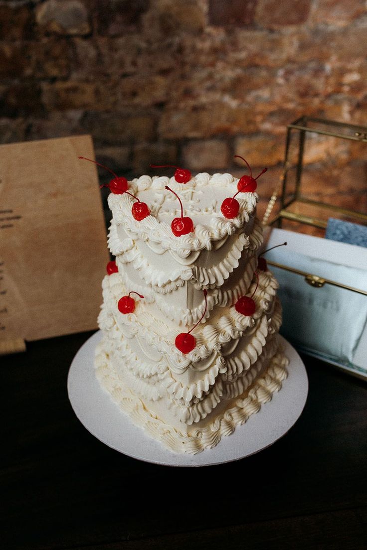 a white cake sitting on top of a table next to a box with red cherries