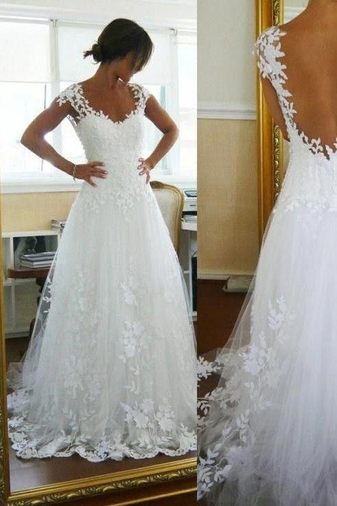 a woman in a white wedding dress looking at her back and standing next to a mirror