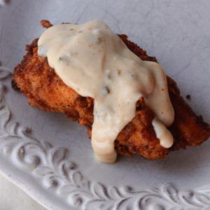 a plate topped with chicken covered in gravy