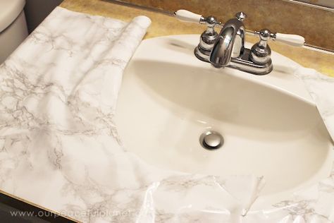 a white sink sitting on top of a bathroom counter next to a toilet paper roll