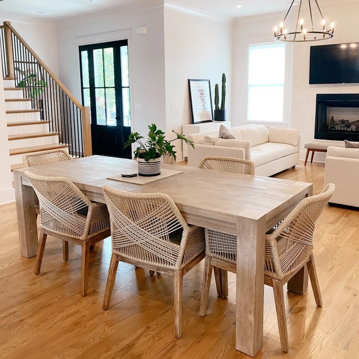 a dining room table with chairs and a couch in front of the stairs leading up to an open floor plan