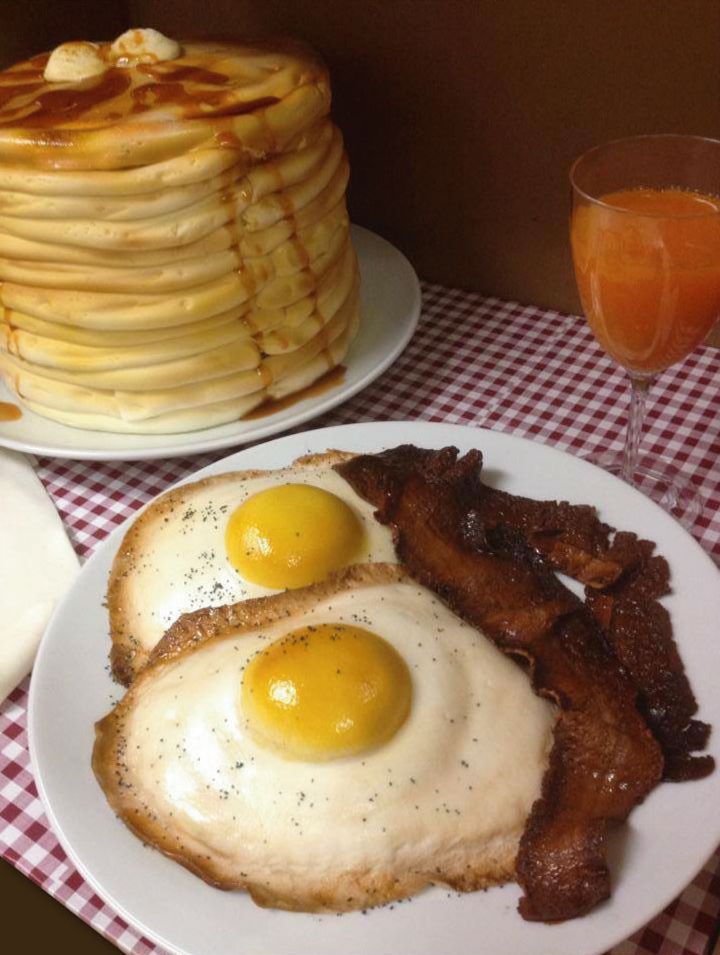 pancakes, eggs and bacon are served on white plates