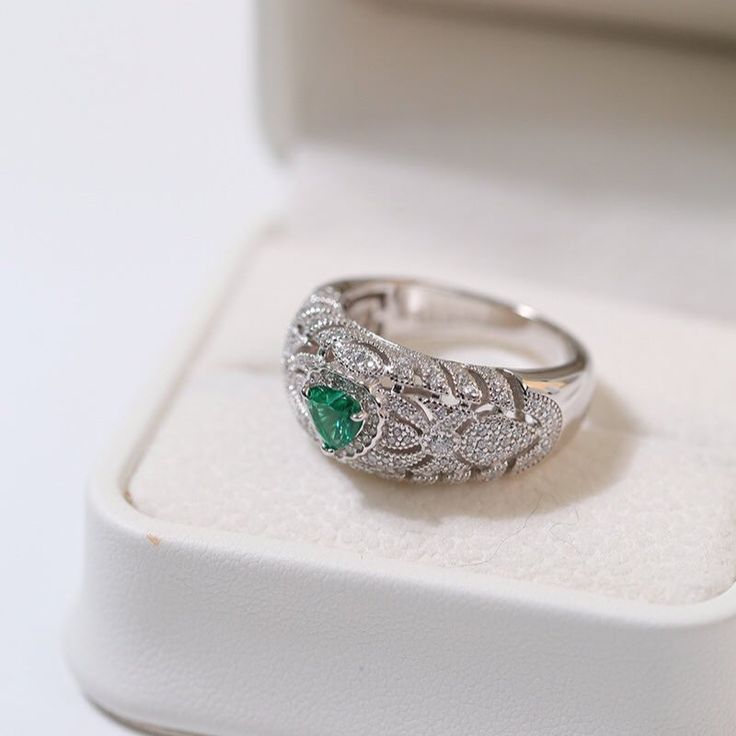 Featuring a heart-shaped emerald centerpiece surrounded by a dazzling halo of diamonds, this delicate ring embodies the essence of vintage elegance. The rich green color of emeralds symbolizes love and vitality, while sparkling diamonds add a touch of glamor. Metal: 18ct Recycled White Gold Plated On Recycled Sterling Silver Gemstone: Cubic Zirconia,Artificial Emerald Gemstone Ring Dimensions: High 10mm Ring Sizes Available: US 6, 7, 8, 9 Weight: 7g Luxury Green Heart Cut Rings, Green Emerald Ring With Diamond Accents For Promise, Green Emerald Promise Ring With Diamond Accents, Green Emerald Ring With Halo Style Fine Jewelry, Elegant Emerald Ring With Halo In Cubic Zirconia, Elegant Emerald Cubic Zirconia Ring With Halo, Green Emerald Diamond Ring With Halo, Elegant Emerald Halo Ring With Cubic Zirconia, Fine Jewelry Green Heart Ring For May Birthstone