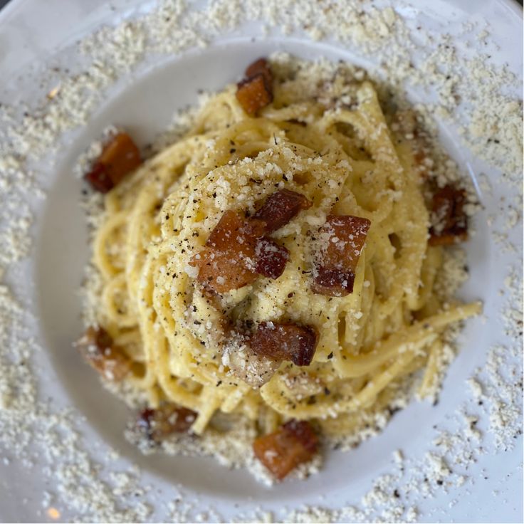 pasta with bacon and parmesan cheese on a white plate