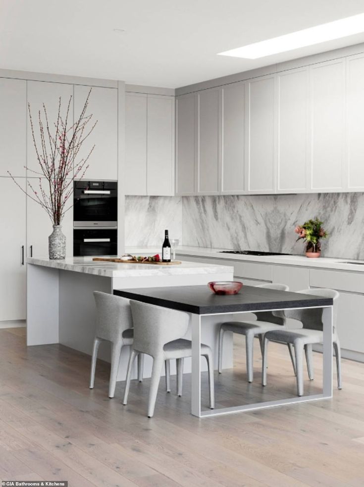 a modern kitchen with white cabinets and marble counter tops, along with an island in the middle