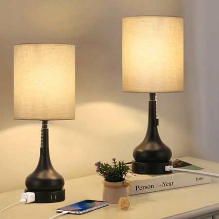 two lamps are sitting on a table next to a book and cell phone in front of them