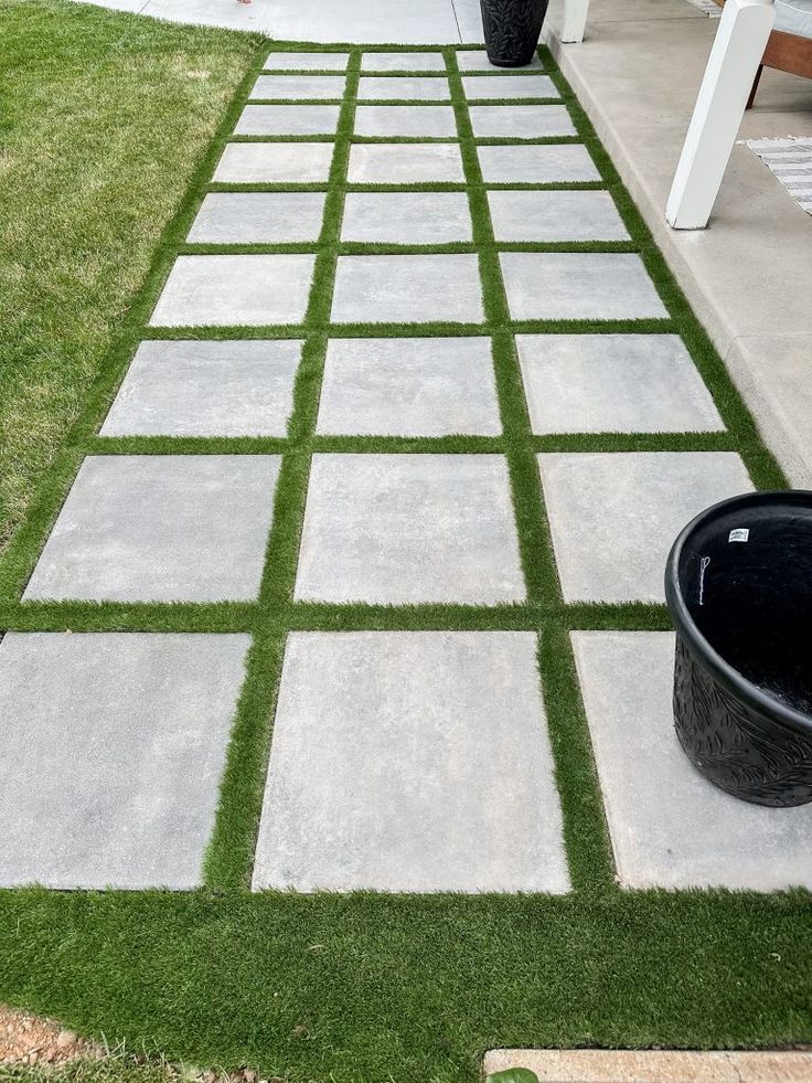 an outdoor walkway made out of concrete blocks and artificial grass