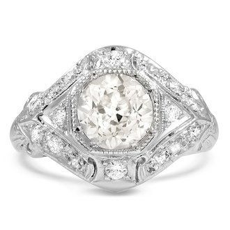 an antique style engagement ring with a large oval diamond center surrounded by smaller round diamonds