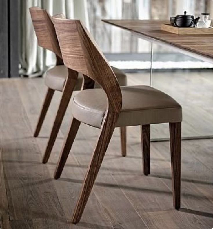 two chairs sitting next to each other in front of a wooden table with cups on it