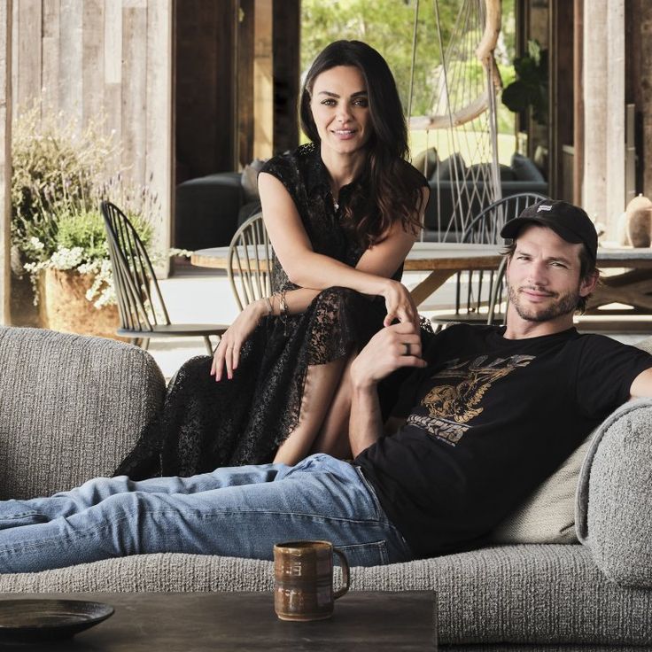 a man sitting on top of a couch next to a woman in a black dress