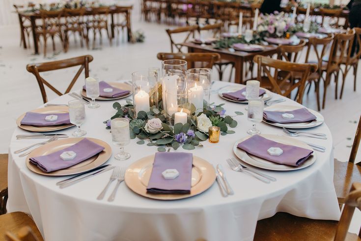 the table is set with purple napkins and place settings