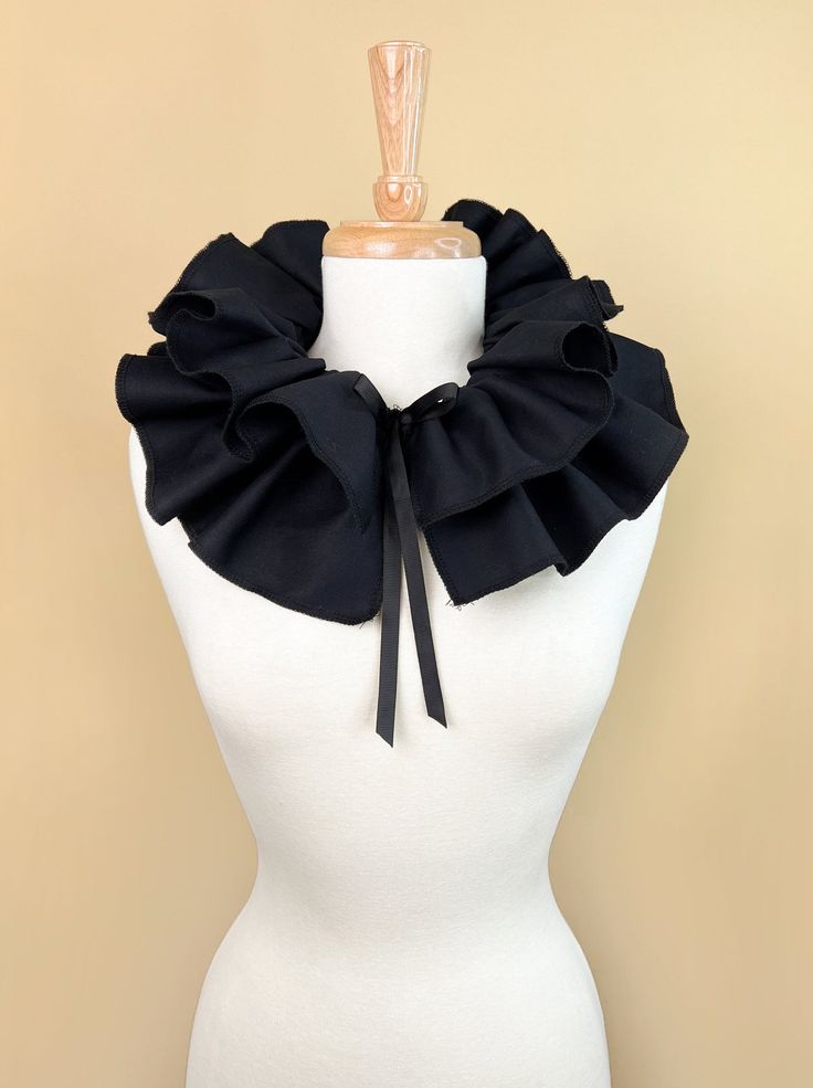 a white mannequin with a black ruffle collar on it's neck