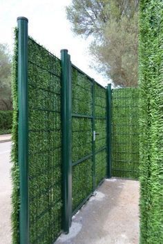 a green fence with some bushes growing on it