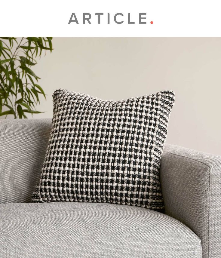 a gray couch with a black and white checkered pillow sitting on top of it