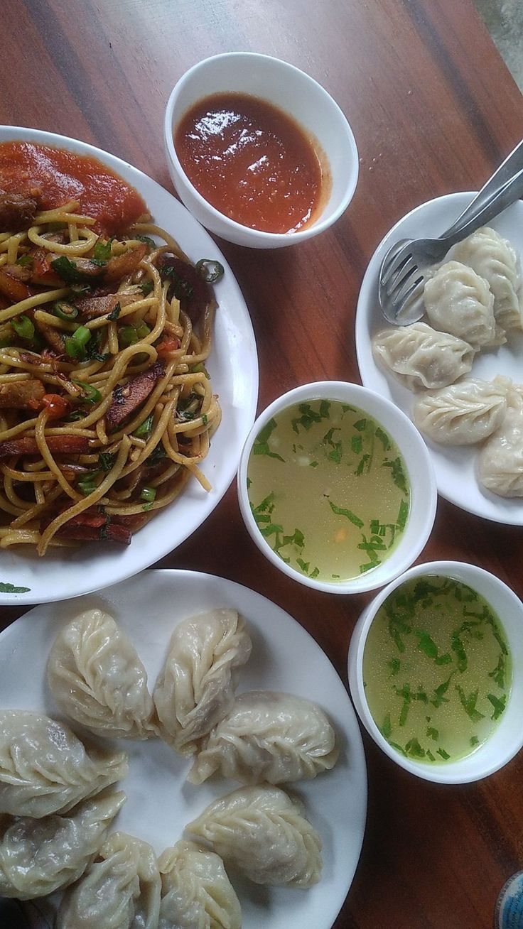 a table topped with plates of food and bowls of sauce