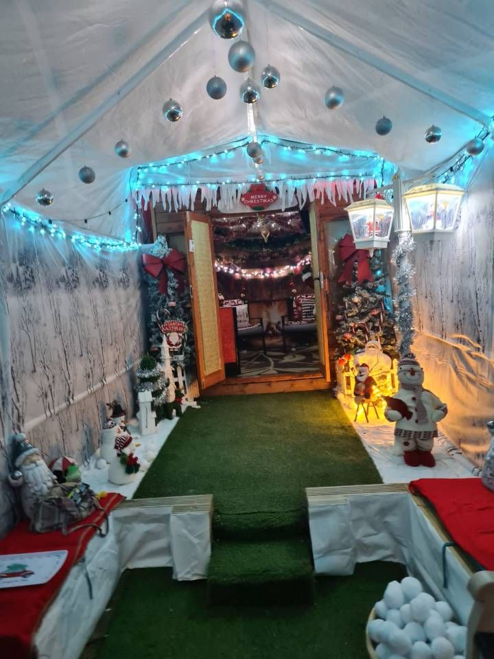 the inside of a tent decorated for christmas with lights and decorations on the ceiling, along with green carpet