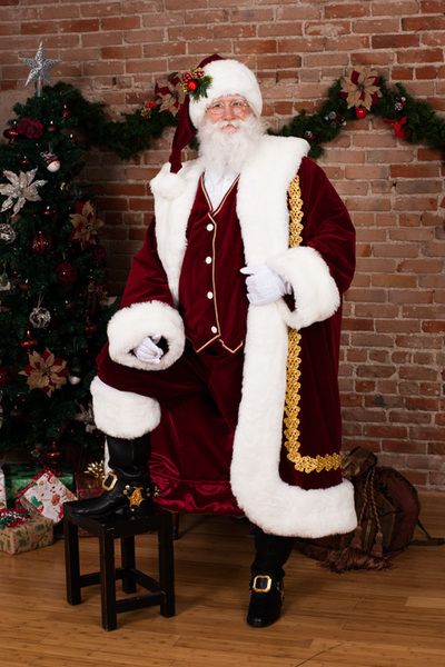 a man dressed as santa claus sitting in front of a christmas tree