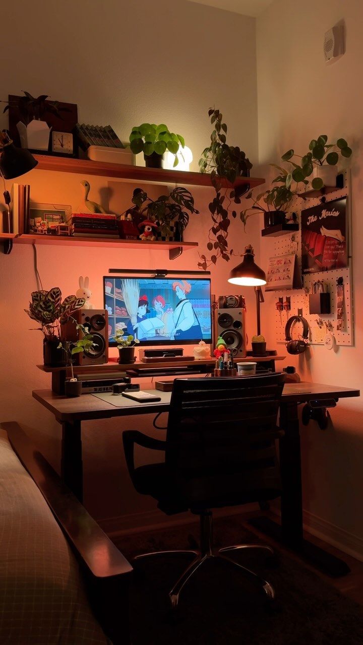 a desk with a computer and plants on it