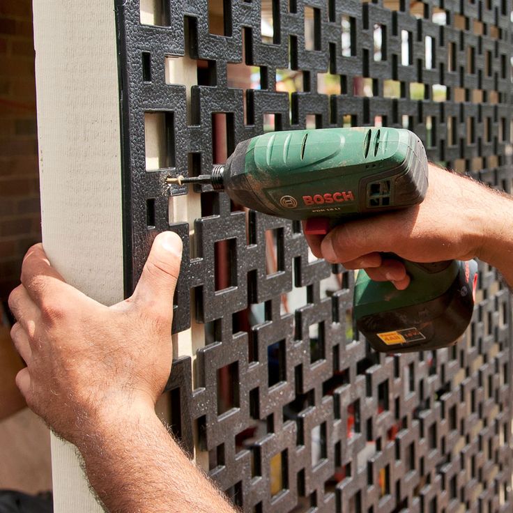 a man is using a drill to attach a decorative panel on a wall with perforated metal panels