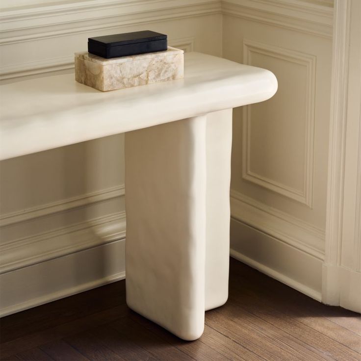 a white marble table with a black book on it's top sitting in front of a wall