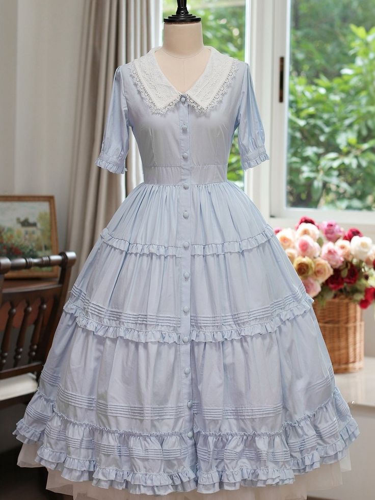 Step into the world of timeless charm with our Blue Front Button Placket Classic Lolita Dress. This exquisite piece is designed to capture the essence of classic Lolita fashion, featuring intricate ruffle trim and delicate pleating details that exude sophistication and grace.  The dress boasts a beautifully crafted front button placket, adding a touch of vintage allure, while the rich purple hue brings a regal elegance to your wardrobe. The removable bowtie on the neckline offers versatility, al Blue Ruffled Dresses For Tea Party, Short Sleeve Ruffled Dress For Tea Party, Fitted Blue Dress With Doll Collar, Feminine A-line Vintage Dress With Ruffles, Vintage Dress With Ruffles And Doll Collar For Summer, Vintage Blue Dress With Doll Collar, Vintage Ruffled Doll Collar Dress For Summer, Elegant Cotton Victorian Dress For Spring, Spring Doll Collar Dress With Buttons