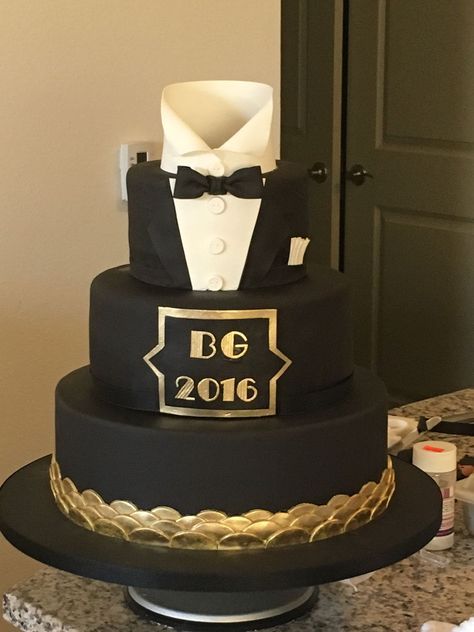 a three tiered black and gold wedding cake with a bow tie on it's top