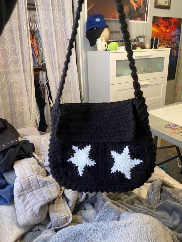 a crocheted black purse with two white stars on it sitting on top of a bed