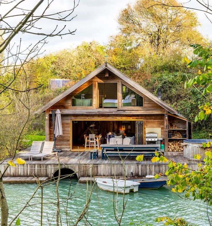 a boat is docked in the water next to a wooden dock with chairs on it