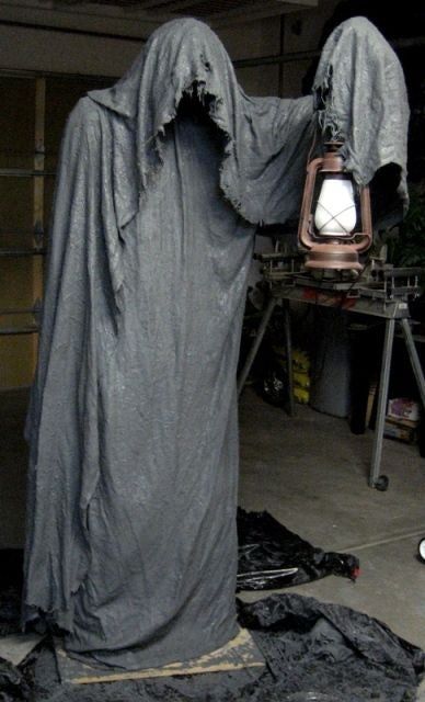 a person dressed as a ghost standing next to a lamp