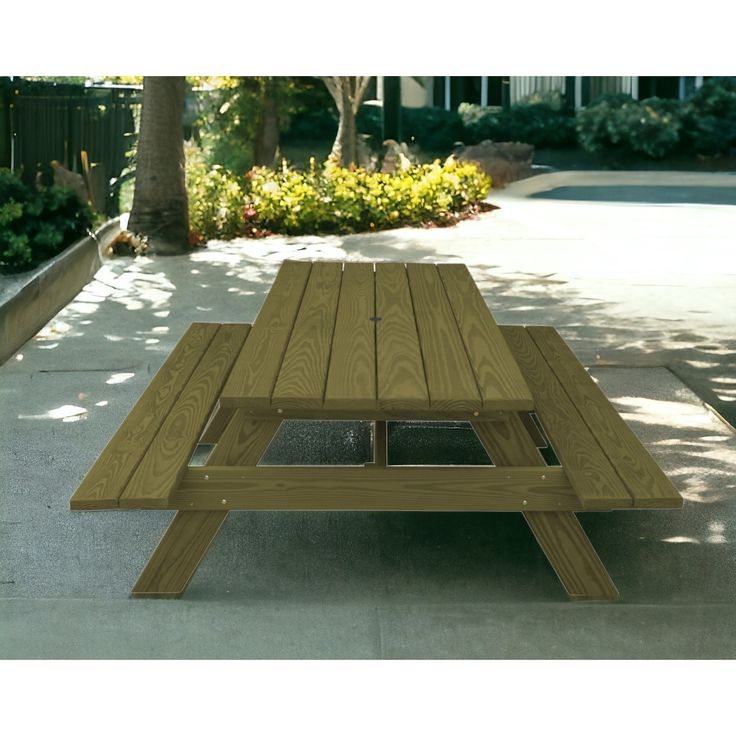 a wooden picnic table sitting on top of a cement floor next to a tree and bushes