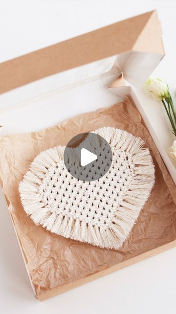 an open box with a white doily in it and flowers on the table next to it