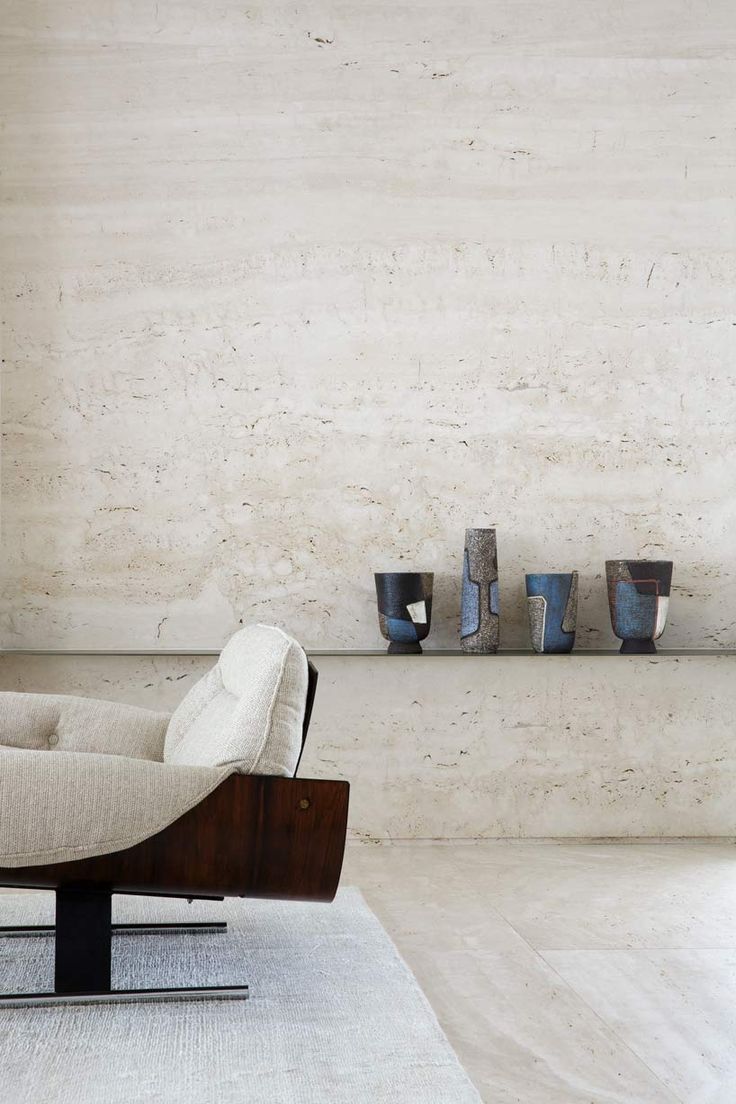 a chair and some vases on a shelf in a room with concrete walls behind it