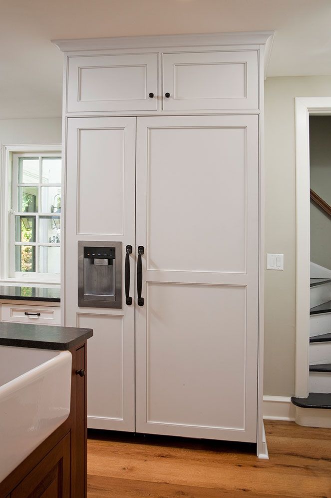 a kitchen with white cabinets and wood floors