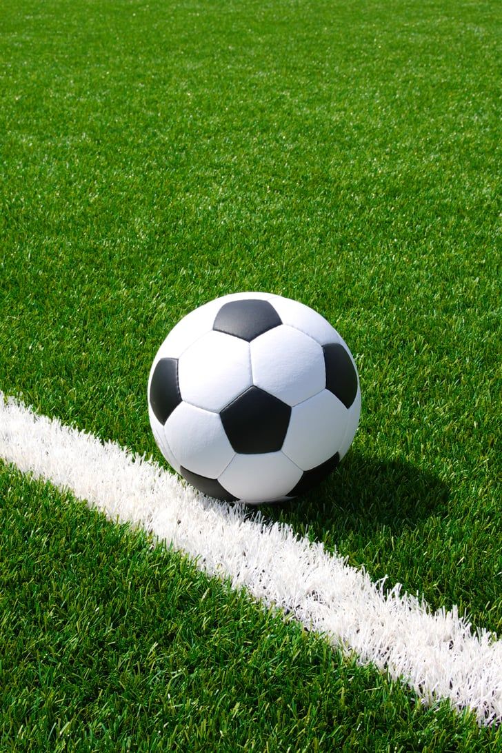 a soccer ball sitting on top of a green field next to a white marker line